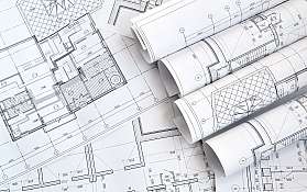 Mehrere aufgerollte Architekturzeichnungen liegen auf detaillierten Bauplänen.