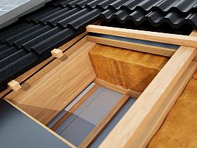 Querschnitt eines Daches mit Holzrahmen, Dämmmaterial und schwarzen Dachziegeln