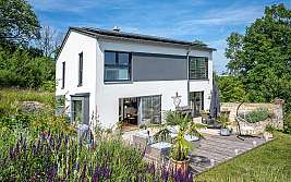 Modernes zweistöckiges Haus mit Holzterrasse, Garten und Gartenmöbeln